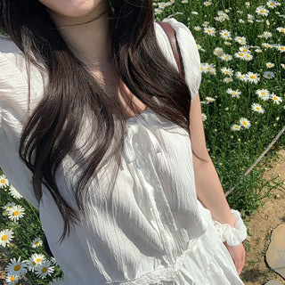 Short-sleeved top with ribbon collar, puff sleeves, and shirring.