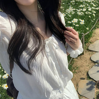 Short-sleeved top with ribbon collar, puff sleeves, and shirring.