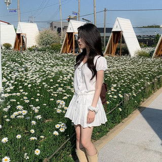 Short-sleeved top with ribbon collar, puff sleeves, and shirring.