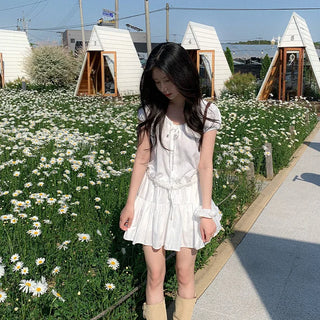 Short-sleeved top with ribbon collar, puff sleeves, and shirring.