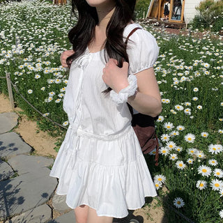 Short-sleeved top with ribbon collar, puff sleeves, and shirring.