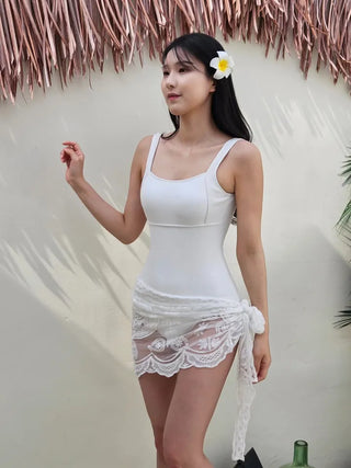 Pure white one-piece swimsuit two-piece set with lace wrap skirt and cover-up and a luxurious vacation pool villa.