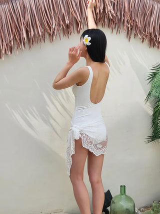 Pure white one-piece swimsuit two-piece set with lace wrap skirt and cover-up and a luxurious vacation pool villa.