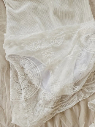 Pure white one-piece swimsuit two-piece set with lace wrap skirt and cover-up and a luxurious vacation pool villa.