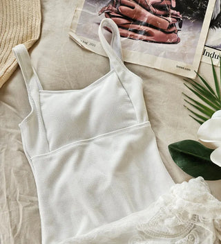 Pure white one-piece swimsuit two-piece set with lace wrap skirt and cover-up and a luxurious vacation pool villa.
