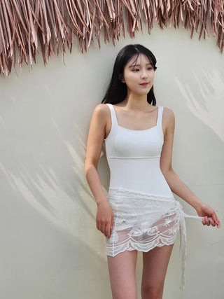 Pure white one-piece swimsuit two-piece set with lace wrap skirt and cover-up and a luxurious vacation pool villa.